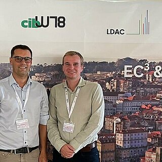 Zwei Personen stehen vor einer Pressewand der European Conference on Computing in Construction (EC³) in Porto. 